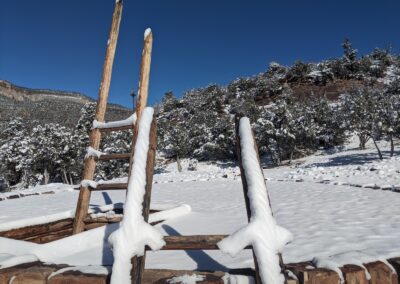 Snow-covered wooden fence rails in a quiet winter landscape under a blue sky.