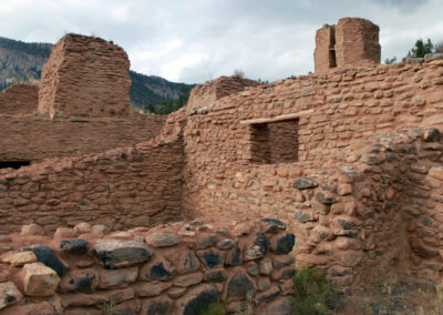 Ancient red stone ruin with crumbling walls and distant mountains.