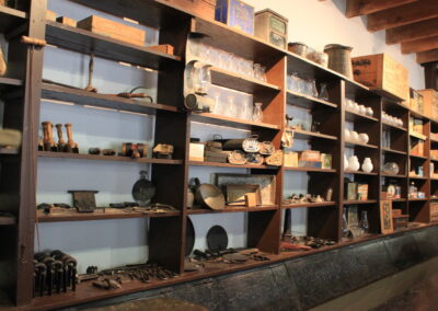Wall of wooden shelves filled with boxes, jars, and assorted artifacts.