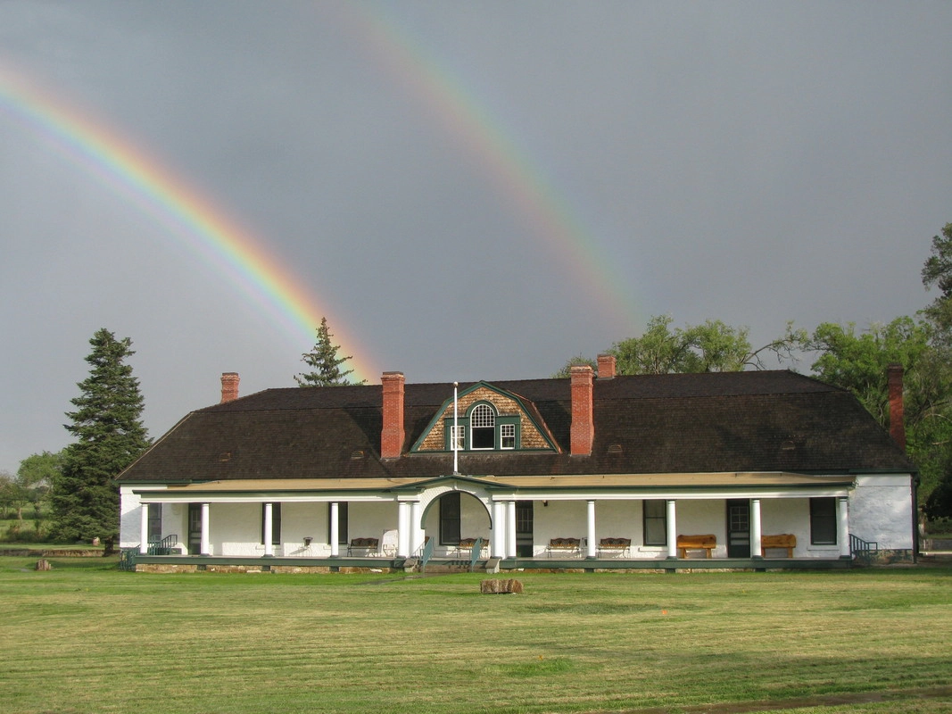 RS2305_Gold-Below-the-Rainbows-scr A double rainbow arching over the white-painted historic main building at Fort Stanton