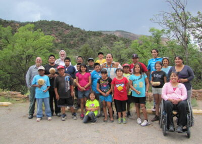 Group of diverse people outdoors, including children and a person in a wheelchair.