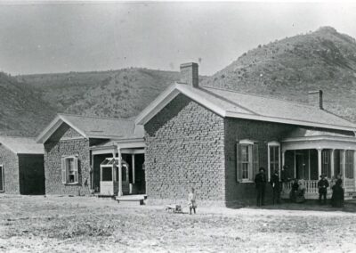 Brick building complex with a covered porch and several people outside, against hills.