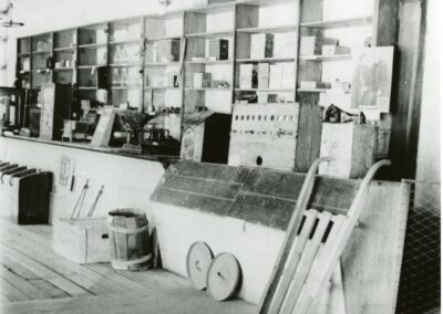 Black-and-white hardware store interior with shelves, crates, and carts.