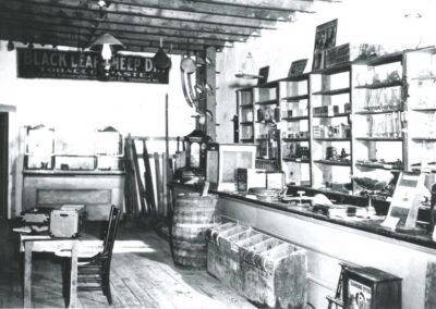 Vintage shop interior in black and white with shelves, display cases, and a counter.