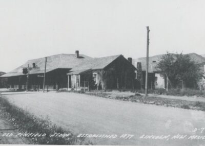 Black-and-white street view of a small rural row of houses along a dirt road.