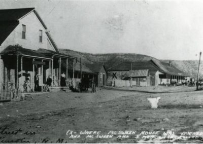 Old rural town street with wooden storefronts and townspeople.