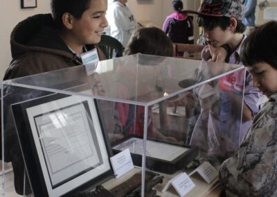 Visitors view a framed document inside a glass display case at a museum.