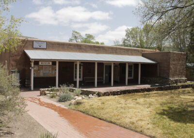 Brick building with a covered porch and brick walkway in a sunny yard.