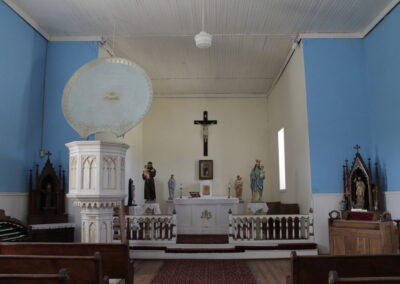 Interior of a blue church with an altar, crucifix, statues, and pews.