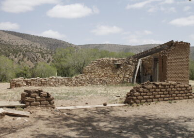 Desert ruin with crumbling brick walls and sparse vegetation.