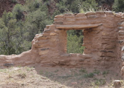 Weathered stone ruin with a rectangular window opening in a dry, wooded hillside.
