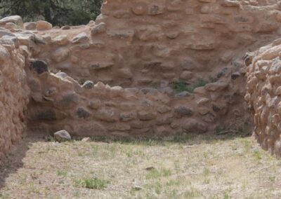 Ruined stone wall in a dry, grassy area with trees in the background.