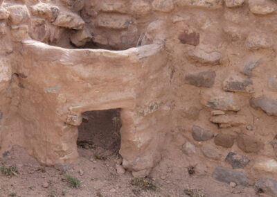 Ancient earthen wall with a small rectangular doorway and a rounded arch opening.