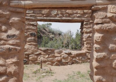 Stone ruin doorway frames a sunlit courtyard beyond.