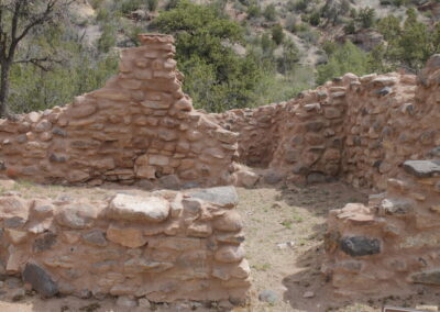 Ruined stone walls of an ancient structure amid a rocky hillside.