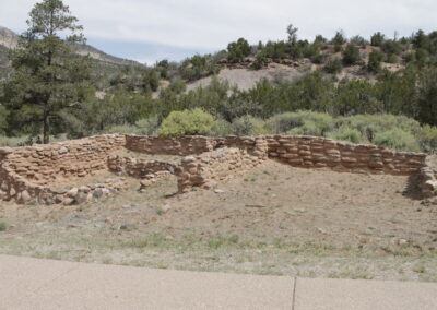 Ruined brick wall in a dry landscape with trees and hills in the background.