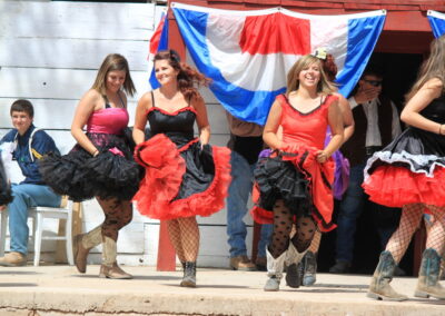 Dancers in red and black dresses perform on an outdoor stage.