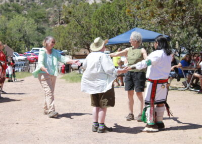 Group of people dancing in a circle at an outdoor festival.
