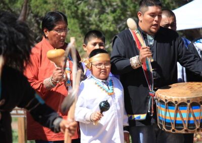 Group of people playing traditional drums at an outdoor cultural festival.