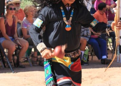 Dancer in a horned mask and colorful outfit performing at an outdoor festival.