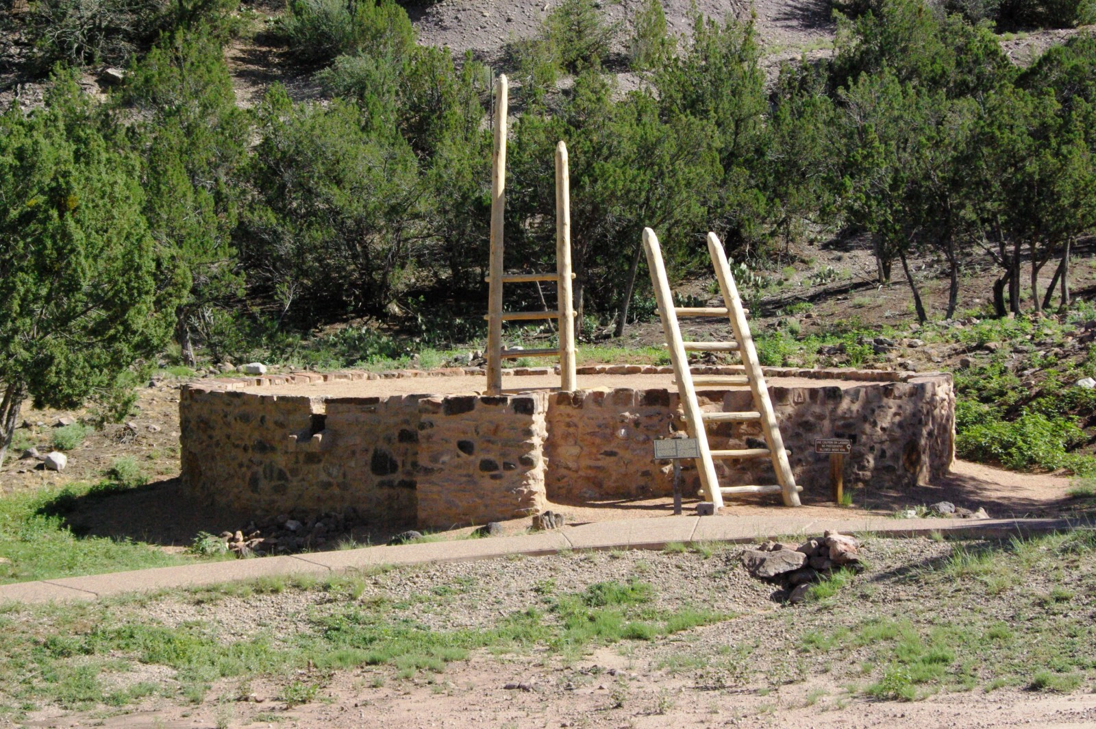 stop4_kiva A reconstructed circular stone kiva with two wooden entry ladders extending above the roofline