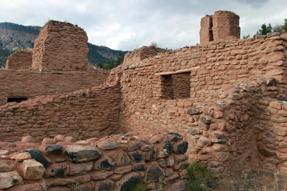 Ancient Adobe Ruins in Hills Ancient red stone ruin with crumbling walls and distant mountains.